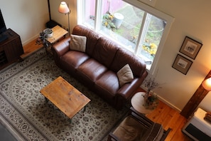 A living room with a brown leather sofa, a wooden coffee table, and a patterned rug.