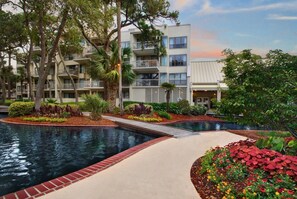 Ein Hotel mit Schwimmbad, angelegtem Garten und mehrstöckigen Gebäuden mit Balkonen.