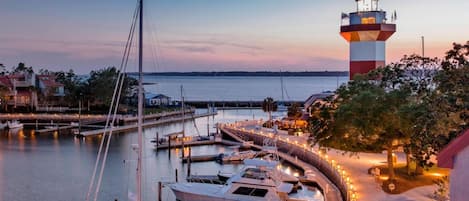 A marina with boats docked, a lighthouse, and a waterfront promenade.