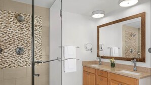 Un bagno moderno con cabina doccia in vetro, un mobile lavabo in legno e uno specchio grande.