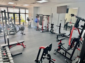 A gym with various exercise equipment, including dumbbells, a bench, and weight machines. - Gulf-Front Condo | Beach Chairs, Balcony & 3 Pools (Panama City Beach)