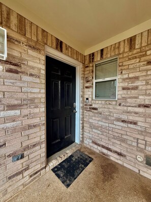 A black door with a doormat, a window with blinds, and a brick wall. - Lux Mins To Cowboys AT&T Stadium, Six Flags, TX Rangers, TX Live (Arlington)