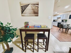 A dining area with a table, two chairs, a potted plant, and a game board. - Lux Mins To Cowboys AT&T Stadium, Six Flags, TX Rangers, TX Live (Arlington)
