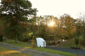 A white tent-like structure in a forested area with a gravel path leading to it. - Pondside Dome | Fire Pit | 30 Min to Penn State (Petersburg)