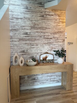 A wooden console table with decorative items against a textured wall.