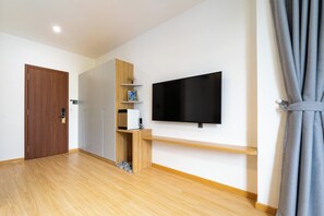 Una habitación con puerta de madera, armario empotrado, televisor montado y zapatero.