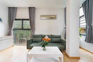 A modern living room with a green sofa, a white coffee table, and a potted plant. - Gia Hai Hotel  (Ho Chi Minh)