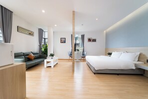 Una habitación de hotel moderna con cama, sofá y zona de comedor con mesa y sillas.