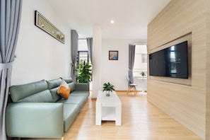 A modern living room with a sofa, a coffee table, a TV, and a plant. - Gia Hai Hotel (Ho Chi Minh)