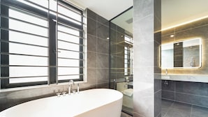 A modern bathroom with a freestanding bathtub, a large mirror, and dark tiled walls. - Gia Hai Hotel  (Ho Chi Minh)