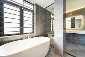 A modern bathroom with a freestanding bathtub, a large mirror, and dark tiled walls. - Gia Hai Hotel (Ho Chi Minh)