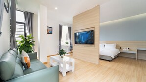 A modern hotel room with a sofa, a coffee table, a TV, and a bed. - Gia Hai Hotel  (Ho Chi Minh)
