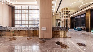 Eine großzügige Lobby mit Marmorboden, einer Rezeption und einem großen Fenster.