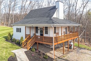 Ein Bungalow mit Veranda, Schornstein und kleinem Garten.