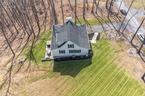 A large house with a steep roof, surrounded by a well-maintained lawn and trees. - 3-bedroom house minutes from Shenandoah - hot tub, kid-friendly and charming (Front Royal)