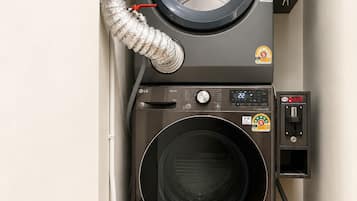 Une machine à laver compacte, conçue pour être fixée au mur, dotée d’un panneau de commande et d’un tuyau.
