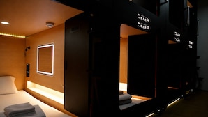 Una camera d'albergo con un letto, un comodino e uno specchio.