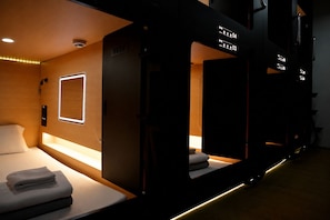 Una habitación de hotel con una cama, una mesita de noche y un espejo.