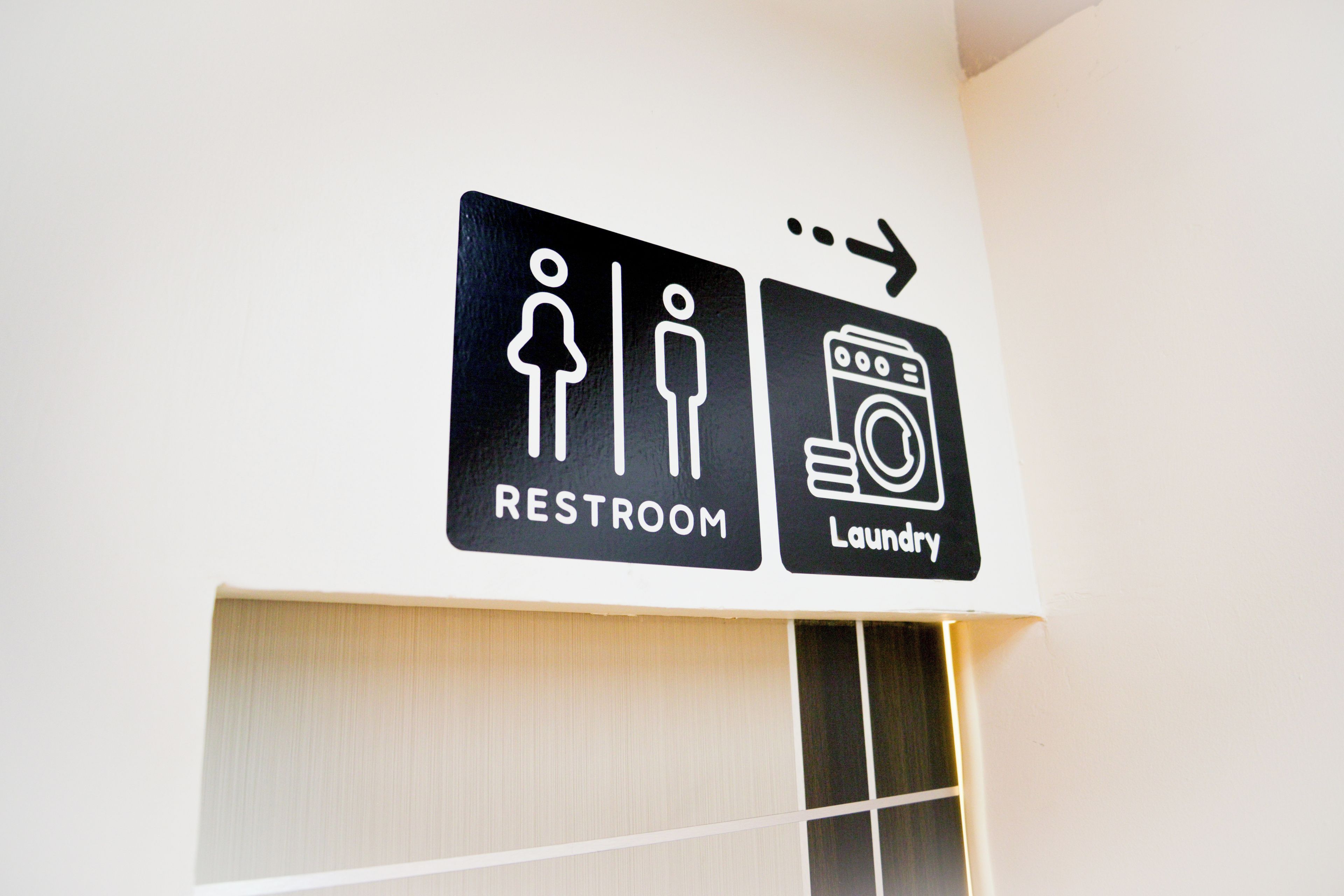 Ein Schild an der Wand, das den Weg zur Toilette und den Wäscherei Einrichtungen weist.