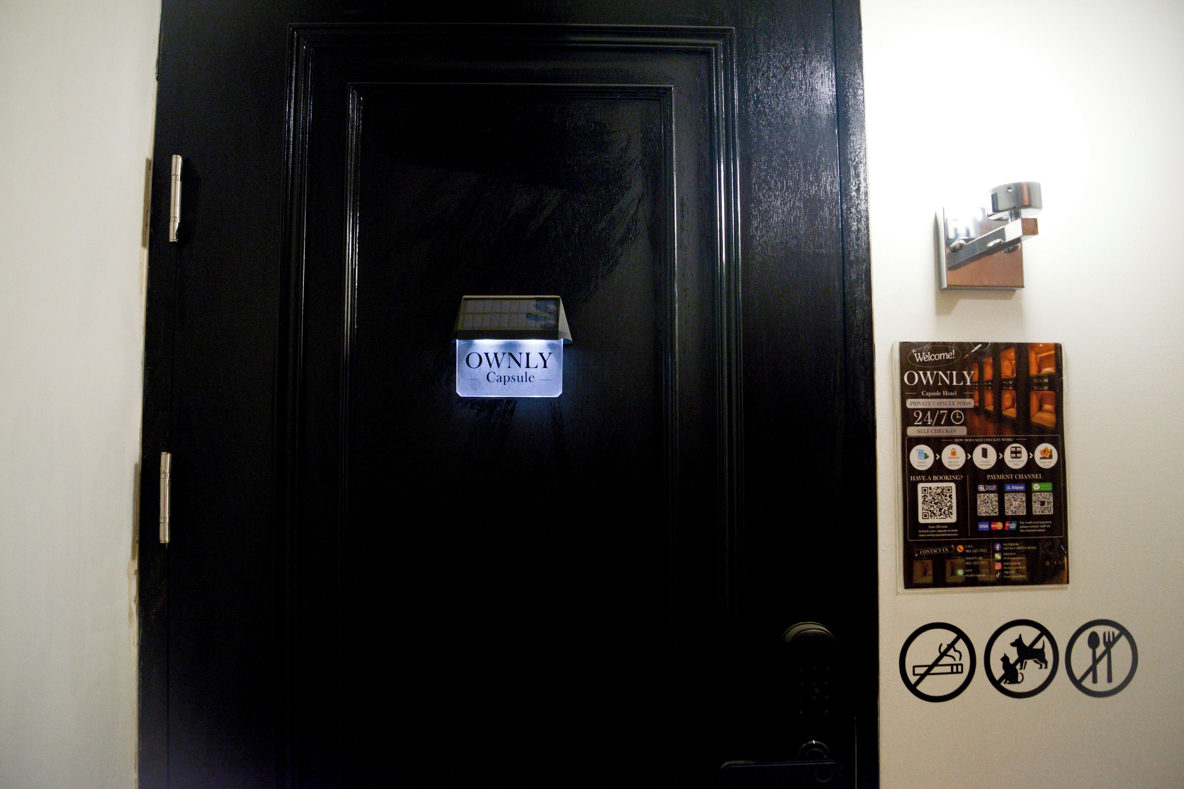 Una puerta negra con un letrero que dice 'OWNLY Capsule'.