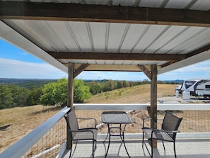 An outdoor patio with a table and chairs, overlooking a hilly landscape. - Bradleyville White House (Bradleyville)