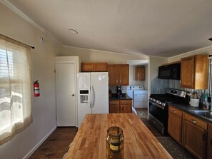Una cocina compacta con refrigerador, microondas, estufa y gabinetes de madera.
