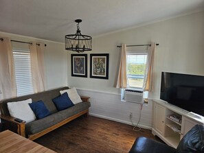 A living room with a sofa, a TV, a chandelier, and two framed pictures on the wall. - Bradleyville White House (Bradleyville)