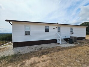 A single-story mobile home with a front porch and a small staircase. - Bradleyville White House (Bradleyville)