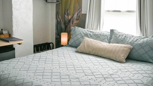 A bedroom with a bed, a desk, a chair, a wall-mounted lamp, and a window with curtains. - Walkable Stay Near Flagler College & Historic Site (St. Augustine)