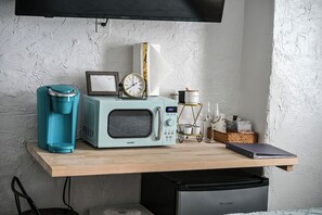 A kitchenette with a microwave, coffee maker, clock, and a small cart with kitchen items. - Walkable Stay Near Flagler College & Historic Site (St. Augustine)