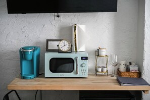 A kitchenette with a coffee maker, microwave, clock, and a small shelf with kitchenware. - Walkable Stay Near Flagler College & Historic Site (St. Augustine)