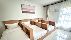 Una camera d'albergo con un grande letto, un comodino, una lampada a parete e una finestra con tende.