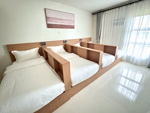 A hotel room with a large bed, a bedside table, a wall-mounted light, and a window with curtains. - Royal Oceancrest Panglao 1 (Dauis)