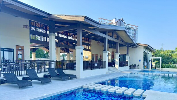 Una piscina con lettini e una zona coperta con vista sull'edificio.