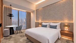 A modern hotel room with a large bed, a round table, and a city view through the window. - The ZHM Premiere Batam (Batam)