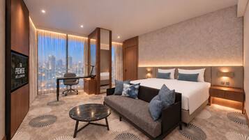 A modern hotel room with a large bed, a sofa, a desk, and a television.