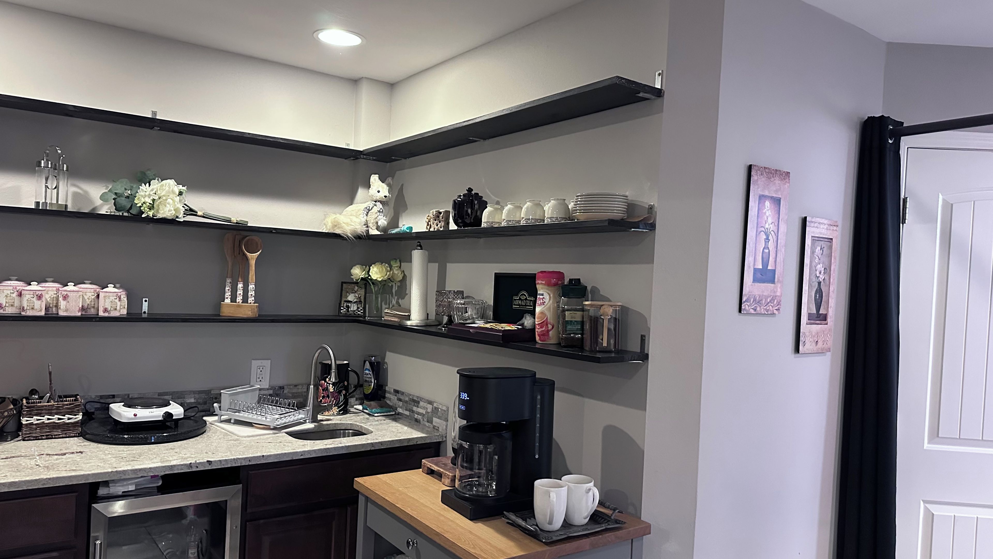 Een keuken met een inbouwoven, een koffiezetapparaat en diverse keukengerei op het aanrecht.