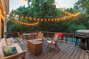 A wooden deck with outdoor furniture, string lights, and a grill. - Cozy 5-Bed Retreat, Heated Spa (Port Republic)