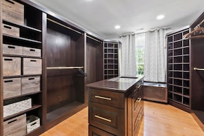 A walk-in closet with multiple storage drawers and shelves, a vanity with a mirror, and a window with curtains. - Cozy 5-Bed Retreat, Heated Spa (Port Republic)