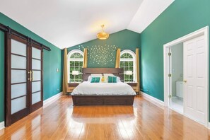 Ein Schlafzimmer mit einem großen Bett, zwei Nachttischen, einem Fenster mit Vorhängen und einer Tür.