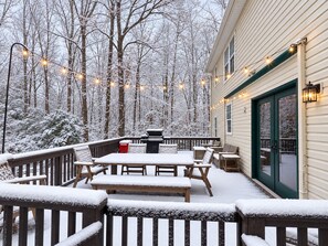 Een sneeuwbedekt terras met tuinmeubilair en lichtjes.