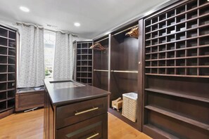Ein begehbarer Kleiderschrank mit mehreren Regalen und Schubladen, einem kleinen Tisch und einer Kleiderstange.