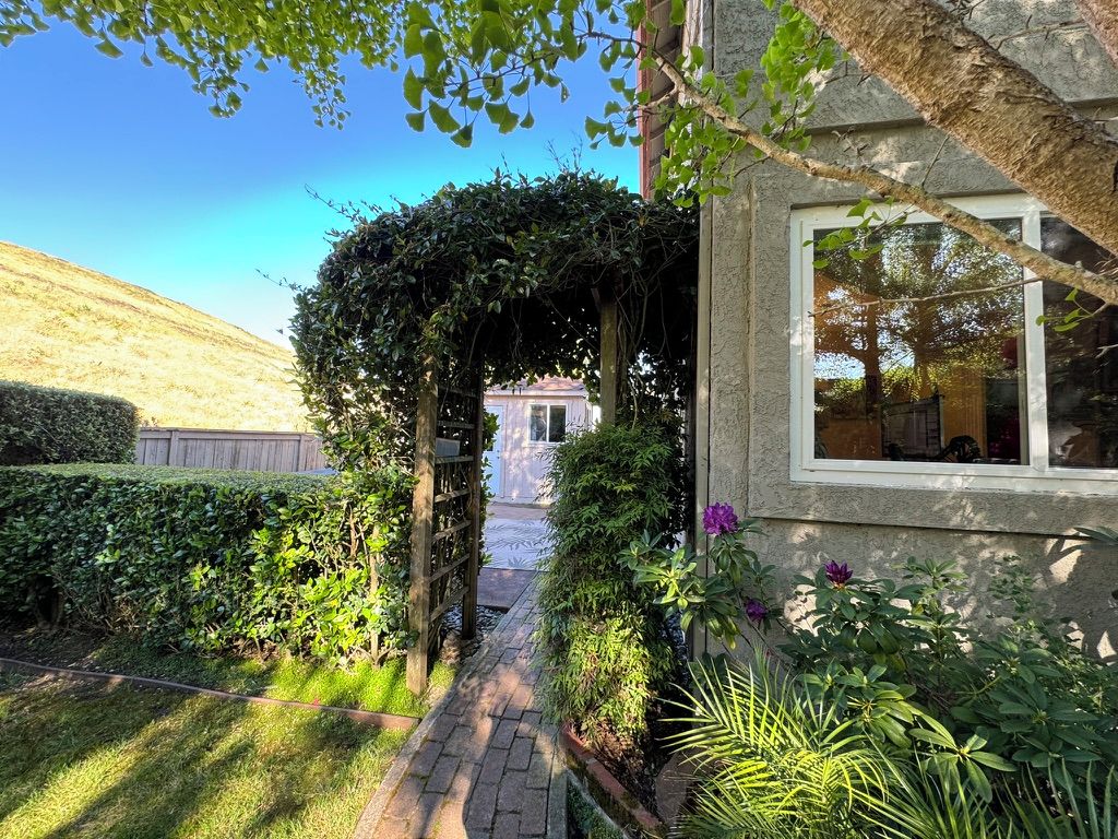 Un sentiero che conduce a un edificio con un giardino e vista su una collina.