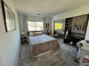 Ein Schlafzimmer mit einem Bett, einem Schreibtisch, einem Stuhl, einem Kleiderschrank und einem Fenster.