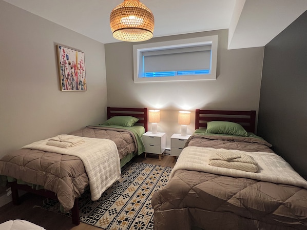 A bedroom with two beds, a patterned rug, a ceiling light, and a window.