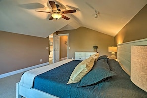 Een slaapkamer met een bed, een plafondventilator, een nachtkastje en een dressoir.