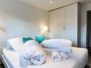 Une chambre d’hôtel avec un lit, des oreillers, une lampe et une armoire.