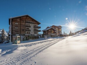 Ein schneebedecktes Skigebiet mit Holzhäusern, blauem Himmel und strahlender Sonne.