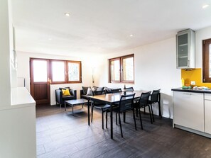 Et moderne køkken med spiseplads, der inkluderer et træbord med stole, en sofa med puder og et skab.
