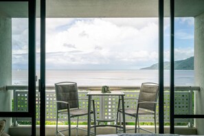 A balcony with a table and two chairs, overlooking a beach and the sea. - Rydges 92B | 9th Floor City & Esplanade Views (Cairns North)